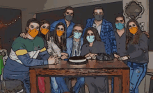 a group of people wearing face masks gather around a table with a cake