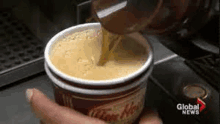 a person is pouring coffee into a cup from a machine .