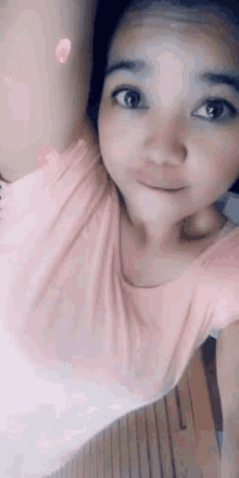 a young woman in a pink shirt is taking a selfie with her arm outstretched .