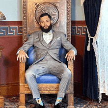 a man in a suit is sitting in a chair with the letter l on the wall