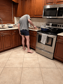 a man is standing in a kitchen with his head in the sink