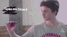 a young man holds a toy in his hand with the words spin to start behind him