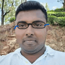 a man wearing glasses and a white shirt smiles for the camera