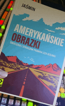 a book titled amerykańskie obrazki sits on a keyboard