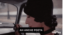 a woman sitting in a car with a sign that says ah anche poeta on it