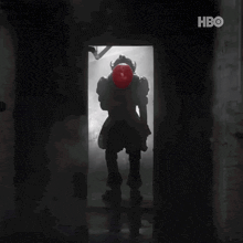 a silhouette of a clown holding a red balloon in a doorway with hbo written on the bottom