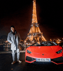 a man standing in front of a red car with a license plate that says ww-934-fn