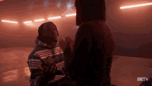 a man in a striped sweatshirt is kneeling down next to a woman in a dark room .