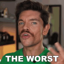 a man with a mustache is wearing a green shirt that says " the worst "