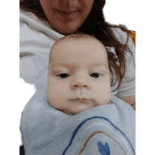 a woman holds a baby wrapped in a blue blanket