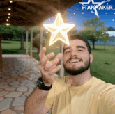 a man is holding up a star shaped light that says starmaker on it