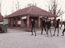 a group of skeletons are dancing in front of a brick building with a sign that says ' a ' on it