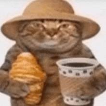 a cat is wearing a hat and holding a cup of coffee and a croissant .