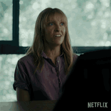 a woman is sitting at a desk with a netflix logo in the corner