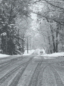 a car is driving down a snowy road with a yellow sign on the right that says yield