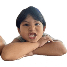 a little boy is making a funny face with his arms crossed .