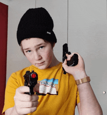 a boy wearing a yellow shirt that says bingo is holding two guns