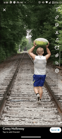 a man is holding a watermelon over his head on a train track