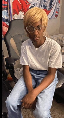 a boy wearing glasses and a white shirt sits in a chair