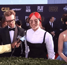 a woman with red hair is being interviewed by a man in front of a wall that says fiji water