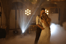 a bride and groom are dancing in a room with smoke coming out of it