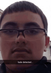 a young man wearing glasses has a fade detected caption on his face