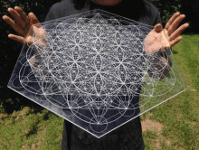 a person is holding a clear acrylic plaque with a geometric pattern on it