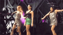 a group of three women are dancing on a stage .