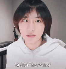 a young man in a white hoodie is watching what .