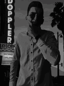 a man wearing sunglasses stands in front of a sign that says doppler