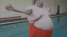 a very fat man is standing next to a swimming pool with his arms outstretched .