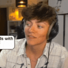 a man wearing headphones and a plaid shirt is making a funny face