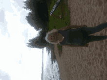 a woman stands on a sandy beach with a kayak in the background