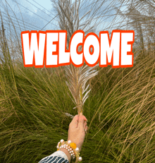 a person holding a feather in front of a field with the word welcome written above it