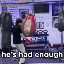 a man in boxing gloves is standing in front of a punching bag that says he 's had enough on it