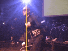 a man in a mask stands on a stage holding a microphone