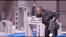 a man in a black karate uniform is kneeling down on a table with bricks stacked on top of each other .