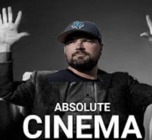 a man with a beard wearing a hat is sitting in front of absolute cinema