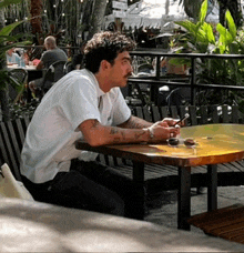 a man sitting at a table with a cell phone in his hand