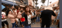 a woman wearing a shirt that says ' i love you ' on it stands in front of a crowd of people