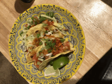 a yellow and gray plate with tacos and lime wedges