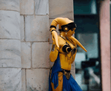 a woman in a yellow and blue costume is leaning against a stone wall