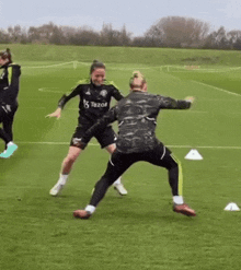 two women are playing soccer on a field .