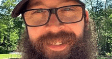 a man with a beard is wearing glasses and a hat .