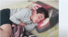 a young boy is sleeping on a bed with a pillow that looks like a car .