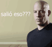 a bald man stands in front of a wall with salio eso written on it