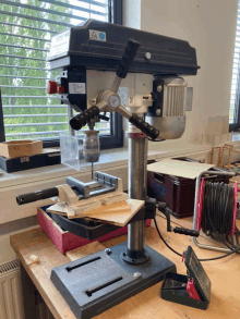 a drill is sitting on a wooden table in front of a window with a warning label on it