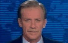 a man in a suit and tie is looking at the camera with a blue background behind him .