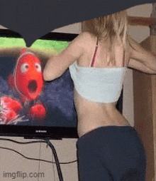 a woman standing in front of a samsung television watching a cartoon