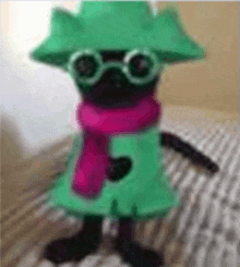 a stuffed animal is wearing a green hat , scarf , and goggles .